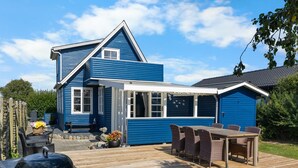 A blue house with a deck, a barbecue grill, and outdoor furniture.