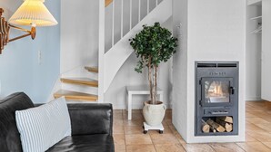 Een moderne woonkamer met een open haard, een trap, een bank en een potplant.