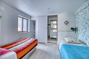 Une chambre avec deux lits, une fenêtre, une armoire et un miroir.