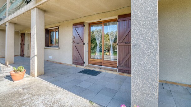 Ein Gebäude mit überdachter Eingangspartei, großen Holztüren und einem Blumentopf.