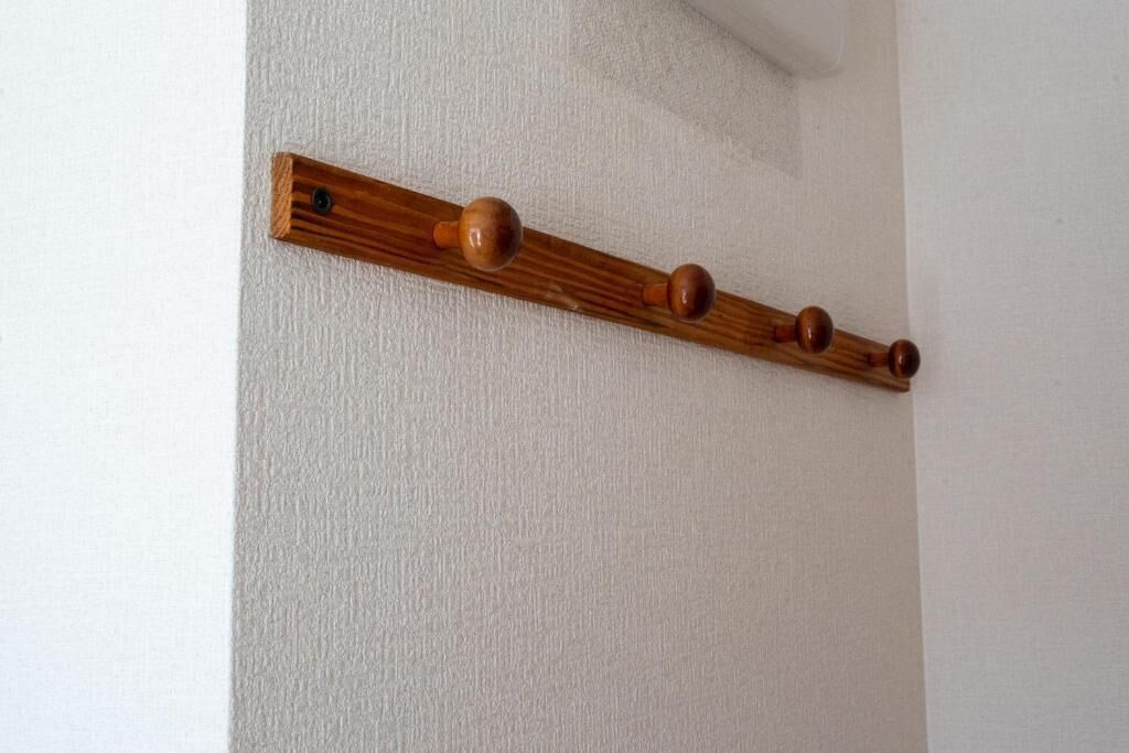 A wooden shelf with three round knobs against a white wall.