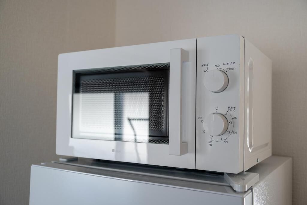 Um forno de micro-ondas branco com duas manivelas de controle e visor digital.
