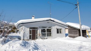A small, single-story house with a snow-covered roof and a visible chimney. - FURANO RELAX STAY BC (Furano)