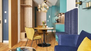 A modern kitchen with a blue accent wall, a dining area with a round table and yellow chairs, and a blue sofa with yellow cushions. - New opening 2025: Beautiful apartment with first-class furnishings! (Sankt Peter-Ording)