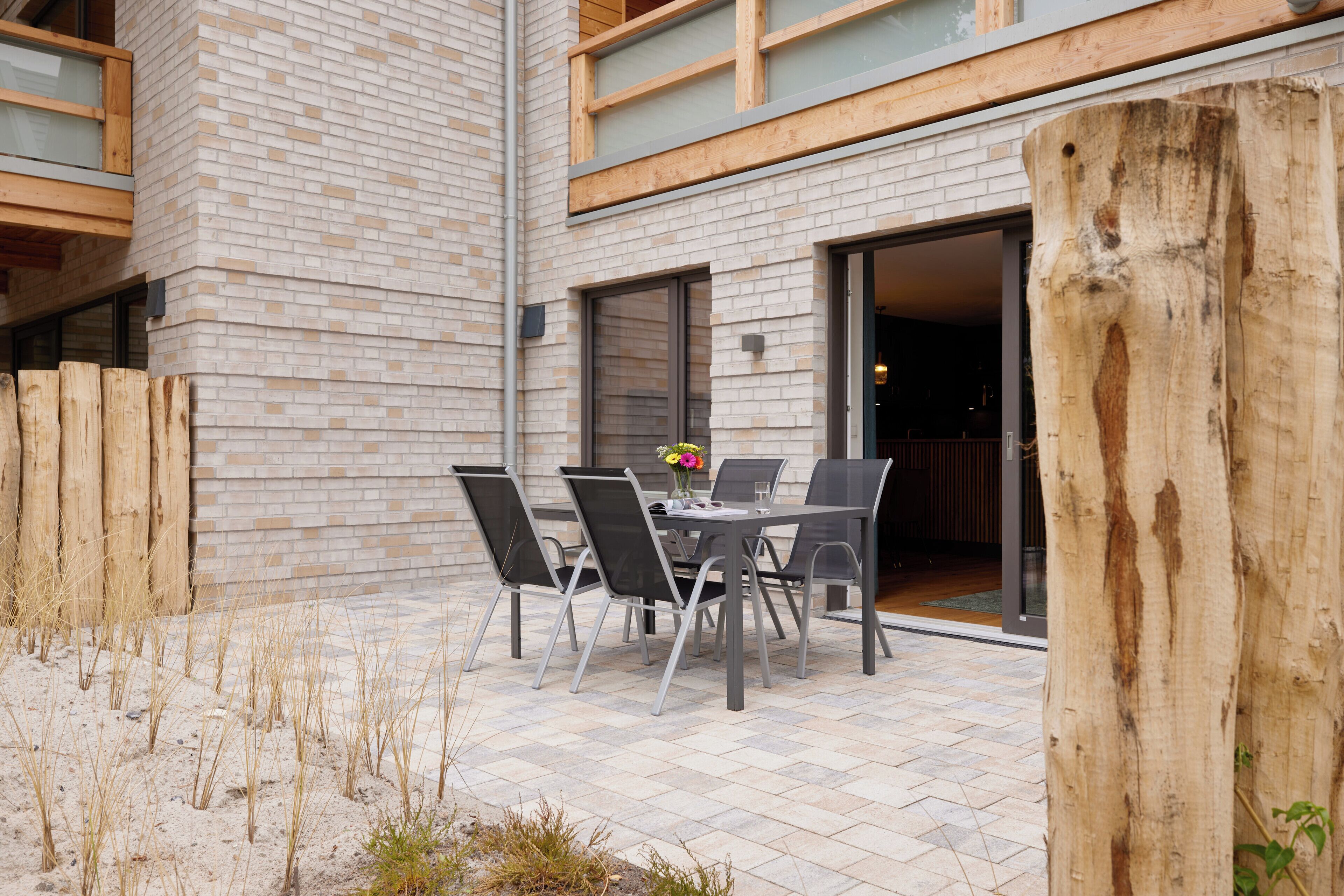 An outdoor patio with a table and chairs, a wooden fence, and a brick building.