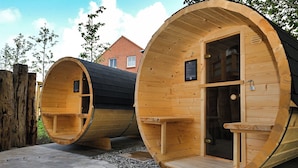 Two wooden sauna cabins with benches and benches, a wooden fence, and a paved area.