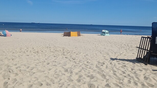A beach with a tent and a chair, and footprints in the sand.