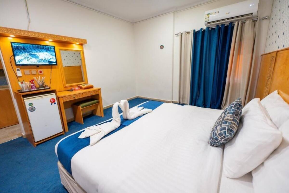 A hotel room with a bed, a desk, a television, and a minibar.