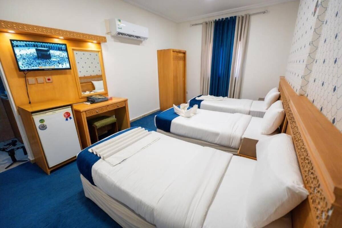 A hotel room with two beds, a TV, a desk, and a wardrobe.