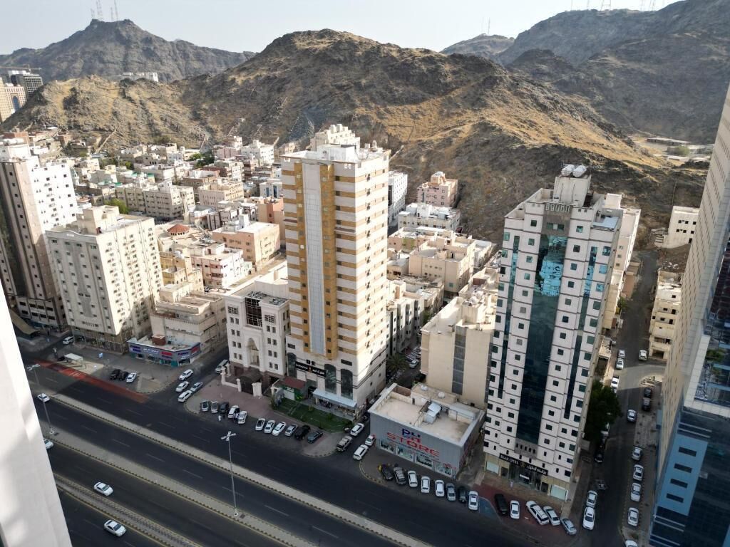Un paisaje urbano con rascacielos, una autopista y terreno montañoso al fondo.