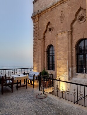 A terrace with a table and chairs, a railing, and a view of the sea. - Yücesoy Konağı  (Mardin)