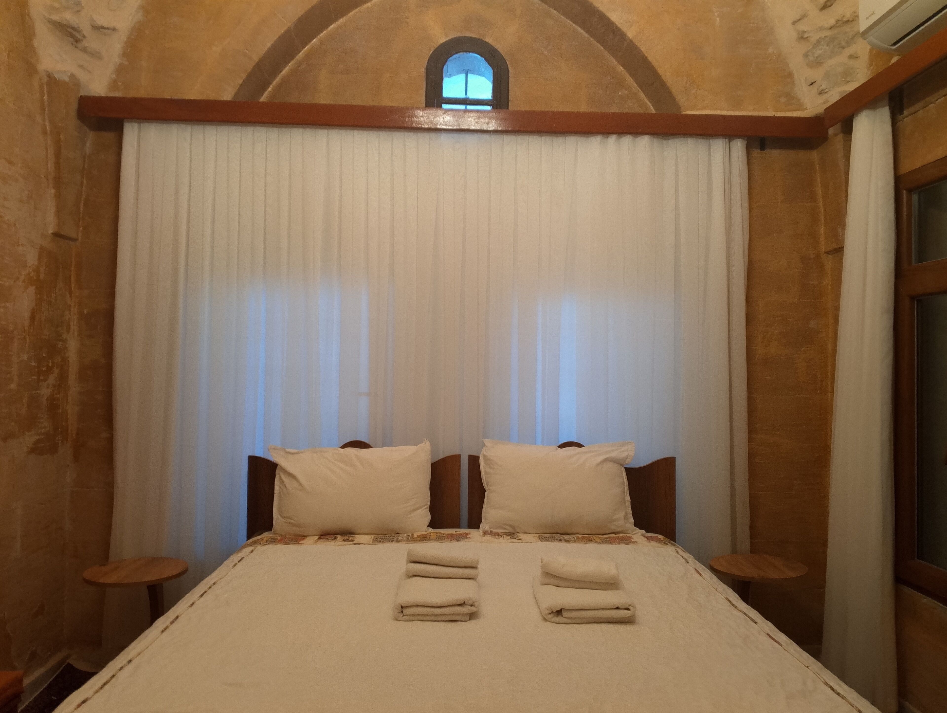Camera da letto con un letto grande, due cuscini, una finestra e una testiera in legno.