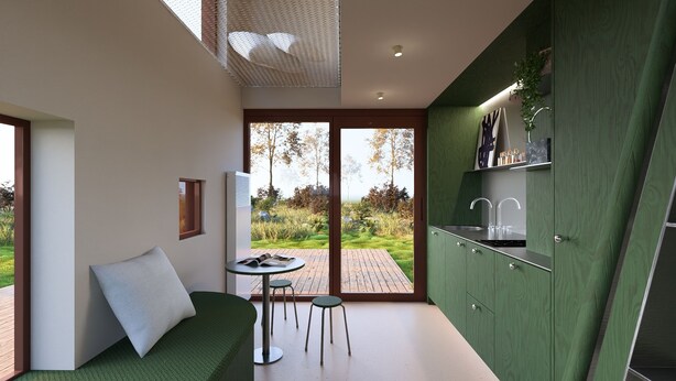 A modern kitchen with green cabinetry, a dining area with a round table and two stools, and a view of a garden through glass doors.