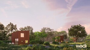 A modern architectural design with two rectangular buildings surrounded by lush greenery and trees.