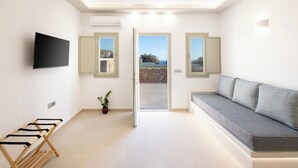 Un salon moderne avec un canapé, un téléviseur fixé au mur et une porte donnant sur un balcon.