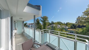 A balcony with a glass railing, a chair, and a table. - "Apartment am Kurstrand" Vacation Rental in Zingst, Right on the Pier (Zingst)