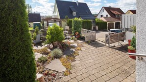 A courtyard with a paved walkway, a car, and a building with a sloped roof. - Apartment 'Ferienwohnung Steffi' with Private Terrace and Wi-Fi (Laichingen)