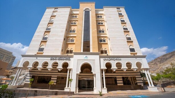 Un hotel de varios pisos con un elemento vertical central, ventanas arqueadas y una fachada simétrica.