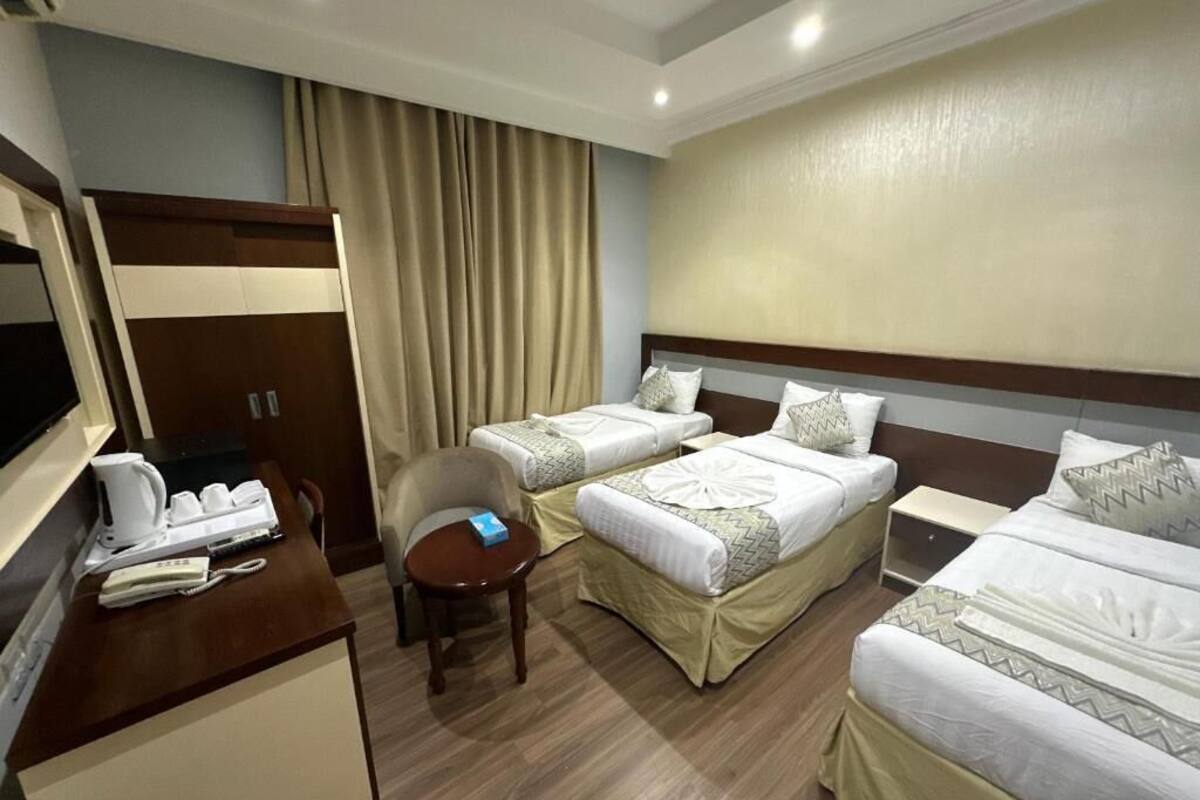 A hotel room with two single beds, a desk with a telephone and a coffee maker, and a chair.