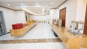 Un hall de hotel con un mostrador de recepción alargado, una estación de café y un espejo grande.