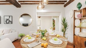 Un comedor con una mesa redonda dispuesta para cuatro personas, rodeada de individuales de mimbre y platos blancos.