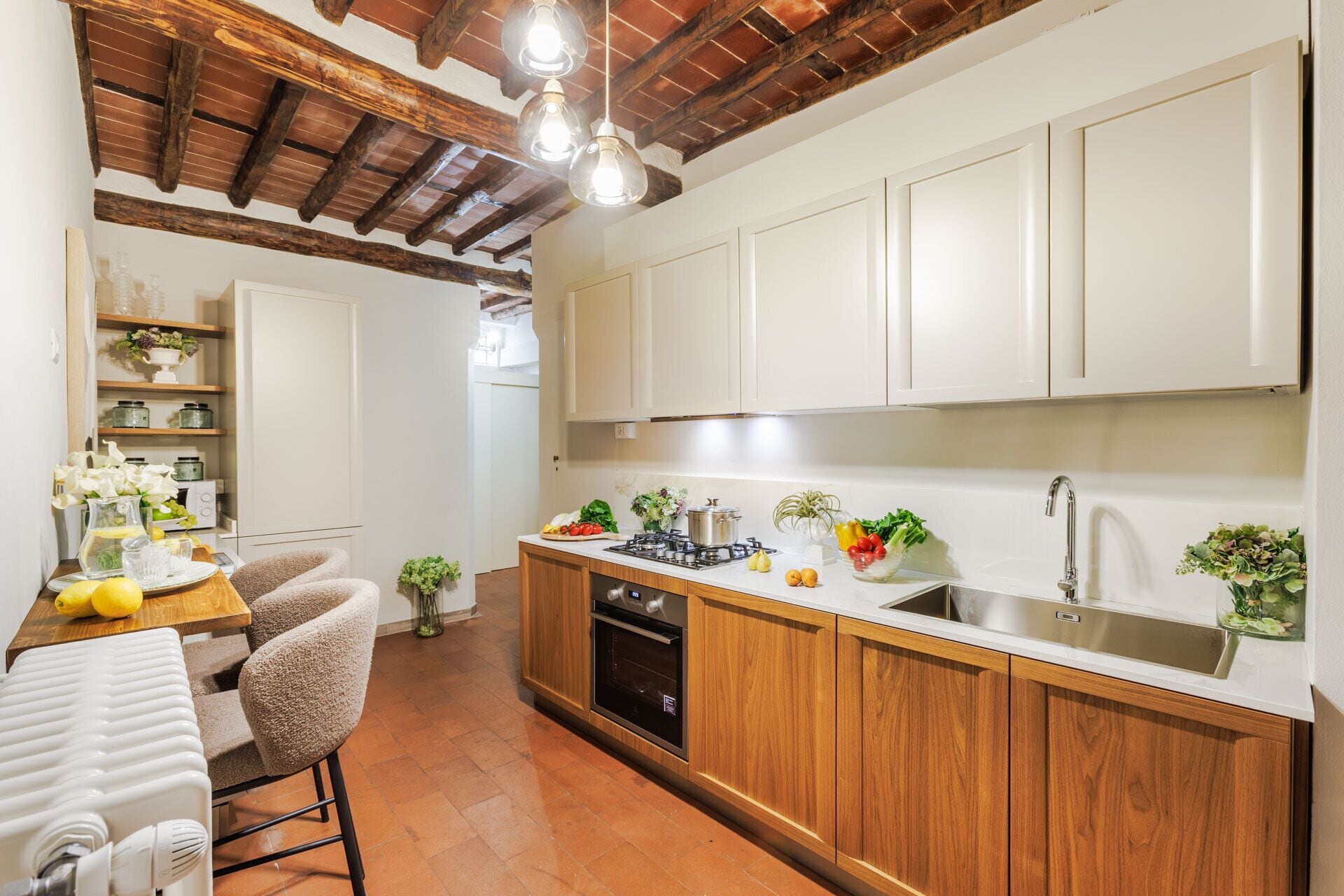 Una cocina con armarios de madera, una estufa y un fregadero. Hay un comedor con una mesa y sillas.