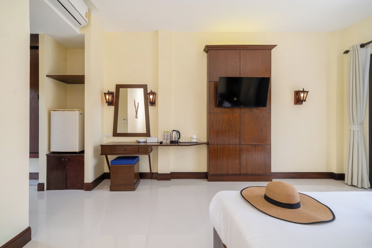 Une chambre d’hôtel équipée d’un lit, d’un bureau, d’une télévision et d’une armoire.