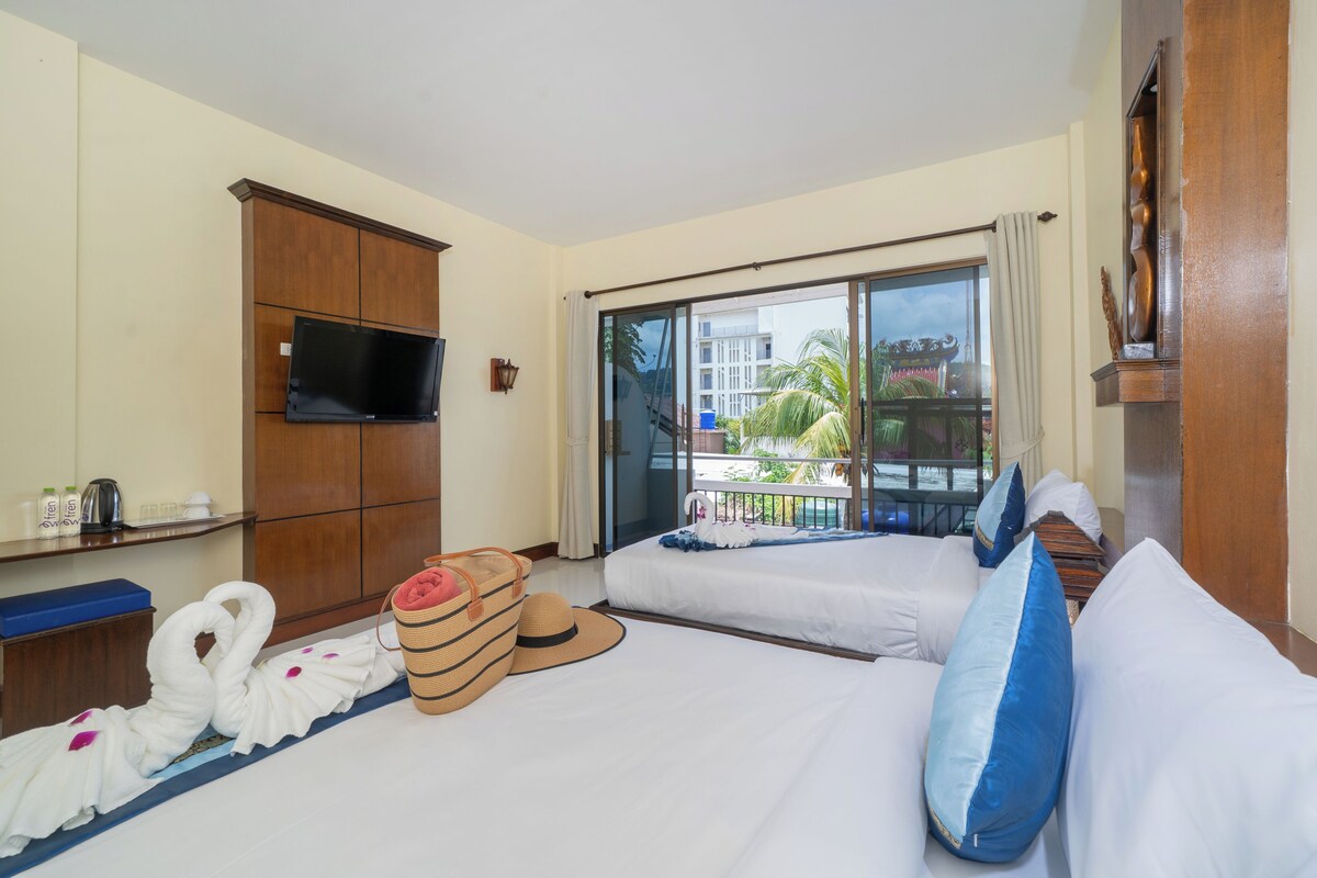 A hotel room with a large bed, a television, a minibar, and a view of the outside.