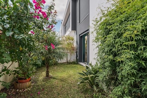 Um edifício moderno com um pequeno jardim, apresentando uma variedade de plantas e um vaso.