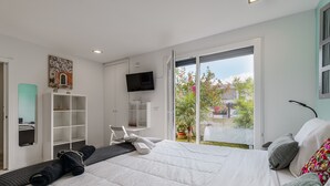 Een moderne hotelkamer met een groot bed, een televisie, een bureau en een balkon met uitzicht op de stad.