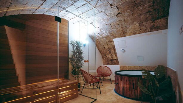 A modern interior with a wooden staircase, a glass partition, and a seating area with red chairs. - Spa Du Palais (Rouen)