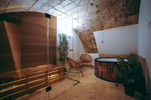 Ein modernes Interieur mit einer Holztreppe, einer Glastrennwand und einer Sitzecke mit roten Stühlen.