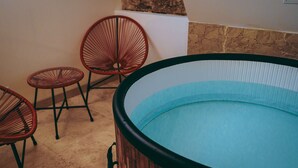 A hot tub with a stone wall and two wicker chairs. - Spa Du Palais (Rouen)