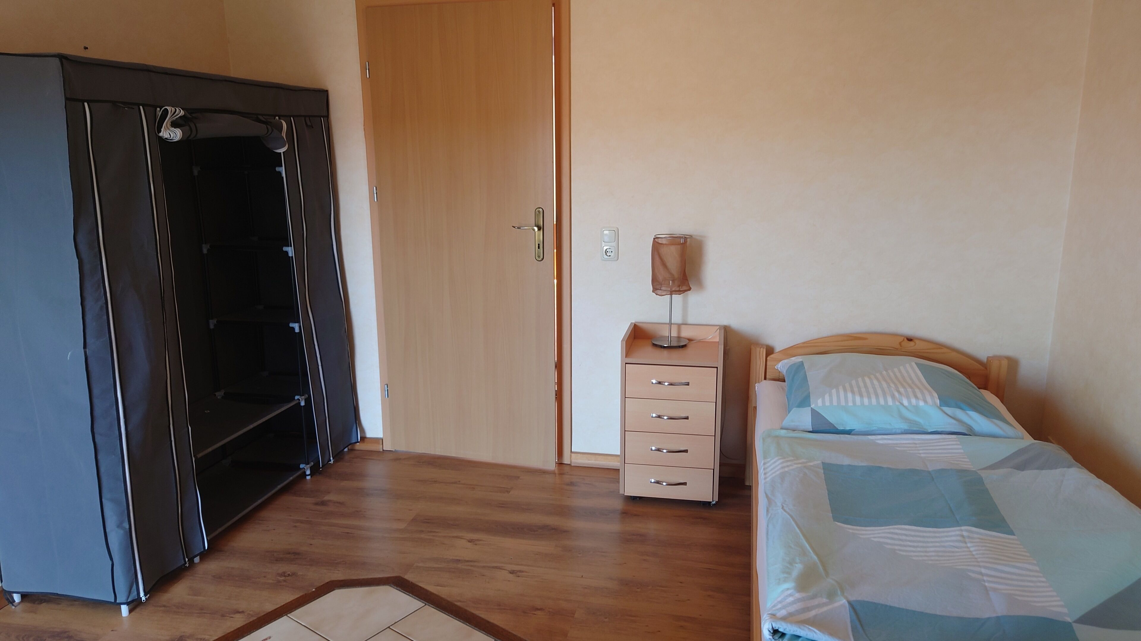 A bedroom with a bed, a nightstand, a dresser, and a wardrobe.