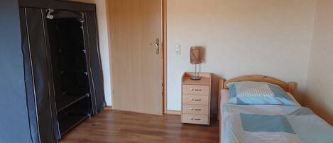 A bedroom with a bed, a nightstand, a dresser, and a wardrobe.