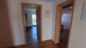 A hallway with wooden flooring leading to a room with a bed and a window. - Apartment 4 Zum Kuhstall Heinrichsberg - Magdeburg (Heinrichsberg)