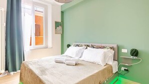 A bedroom with a bed, a window, and a green wall.