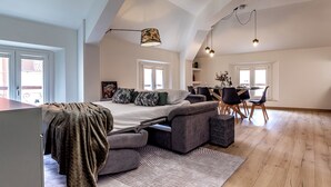 En rummelig loftlejlighed med en stor seng, et spisebord og et køkken.