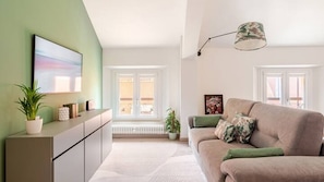 A modern living room with a sofa, a sideboard, and a large window.