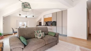 A modern living room with a sofa, a dining area, and a kitchen in the background. - Green Lux-Via Canalino| Pass ZTL&Parking A/C WiFi (Modena)