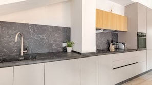 A modern kitchen with a marble backsplash, stainless steel sink, and built-in oven.