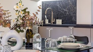 Et moderne spiseområde med marmor bagvæg, en hvid vase med blomster og en vinflaske.
