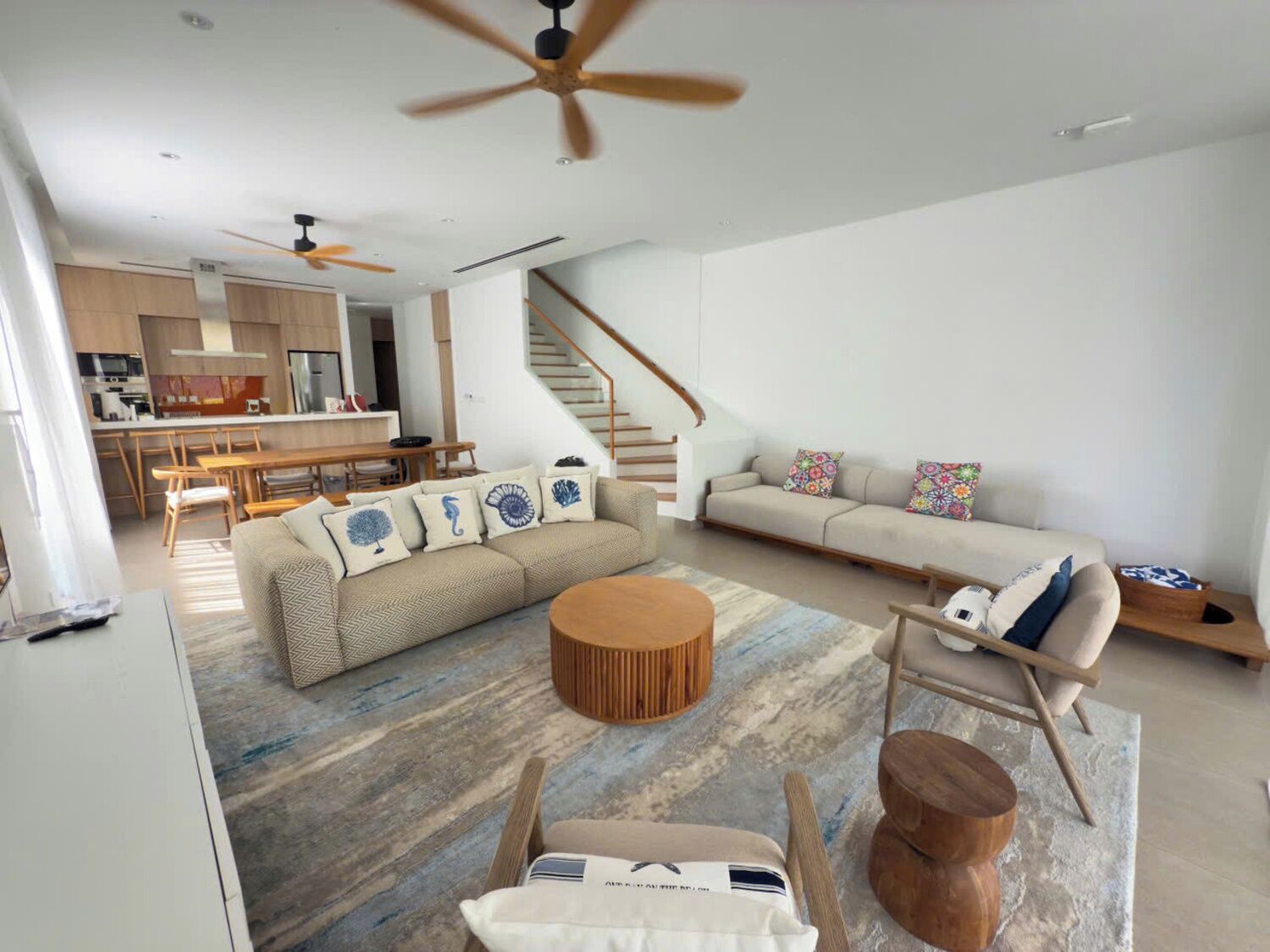 A modern living room with a sofa, coffee table, and a dining area with a wooden table and chairs.