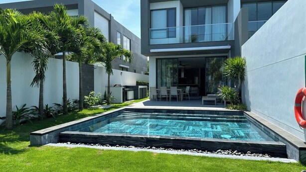 A modern residential building with a swimming pool, outdoor seating, and lush greenery. - Glenwood Sanctuary Villa 85 Ho Tram (Ho Chi Minh City)