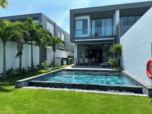 A modern residential building with a swimming pool, outdoor seating, and lush greenery. - Glenwood Sanctuary Villa 85 Ho Tram (Ho Chi Minh City)