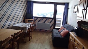 A compact living space with a dining table, a sofa, and a television. - Spacious Apartment in Super Besse for 6 with WIFI (Besse-et-Saint-Anastaise-Super Besse)