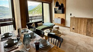 Un coin repas avec une table dressée pour quatre personnes, un canapé et un téléviseur fixé au mur.