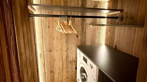 Une buanderie avec des murs en bois, un lave-linge et un étendoir.