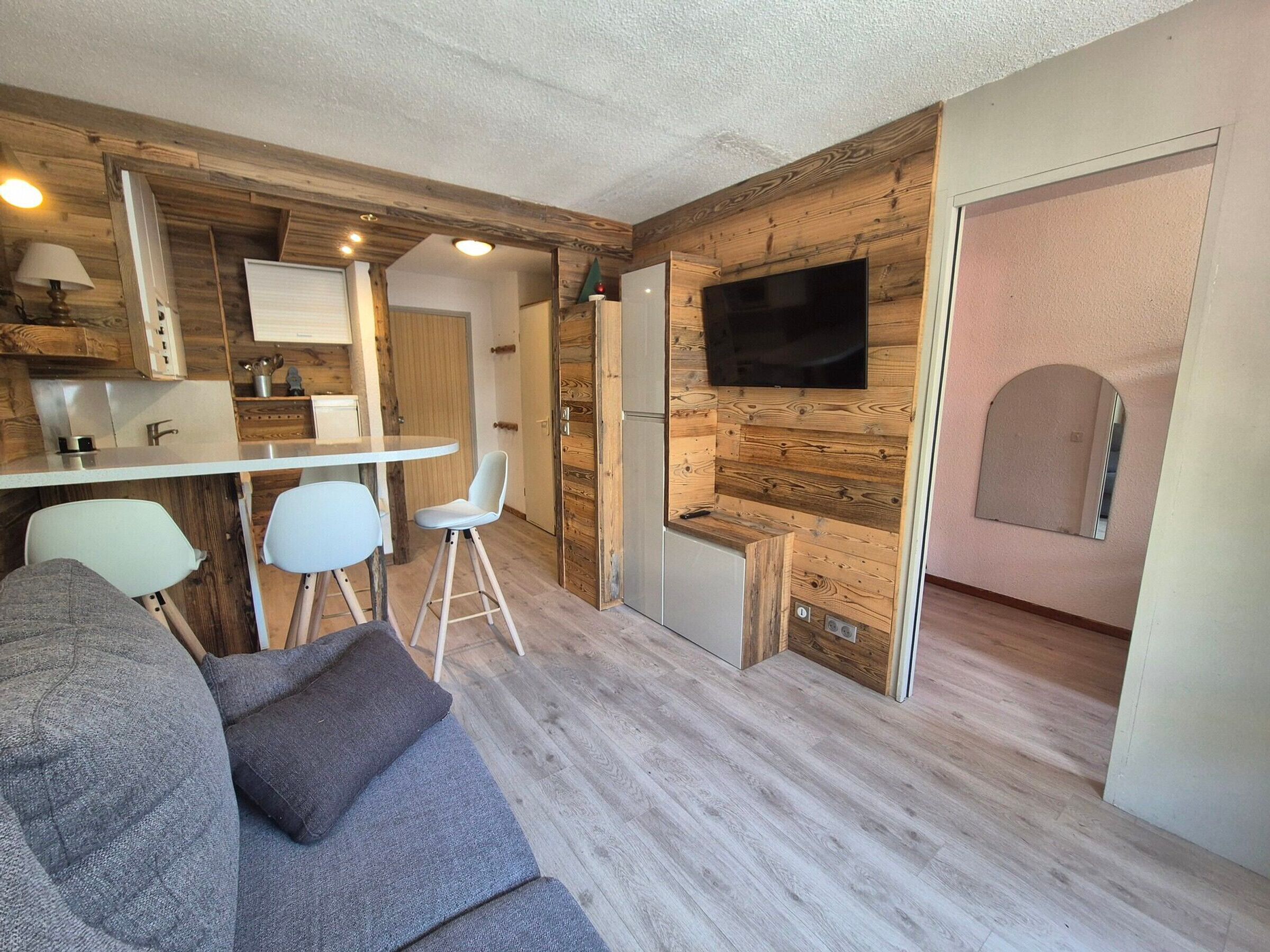 Un espacio habitable compacto con kitchenette, zona de comedor y sala de estar con sofá y sillas.