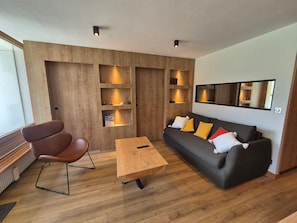 A modern living room with a wooden wall, a sofa, a coffee table, and a chair.